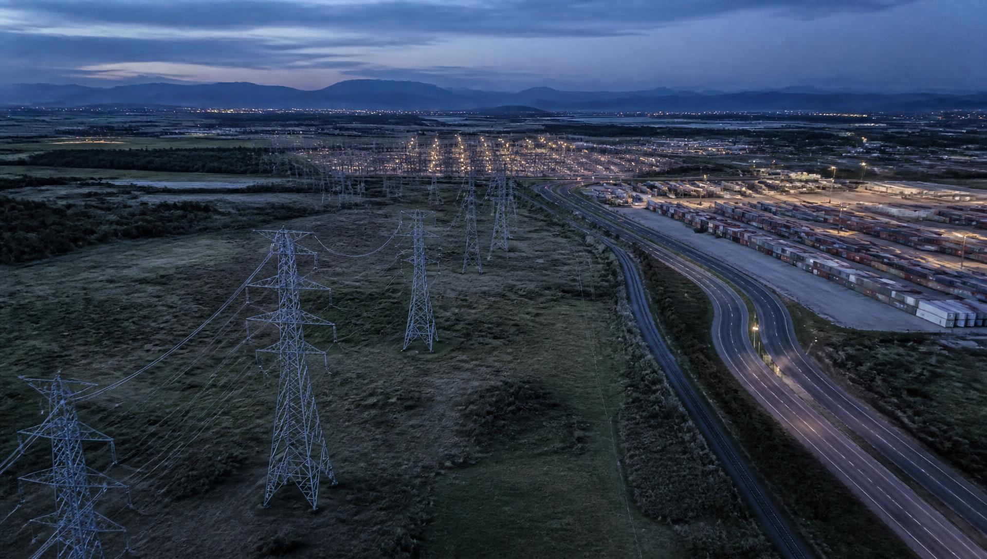 Aerial view at dusk of transmission lines, a highway and an intermodal logistics yard